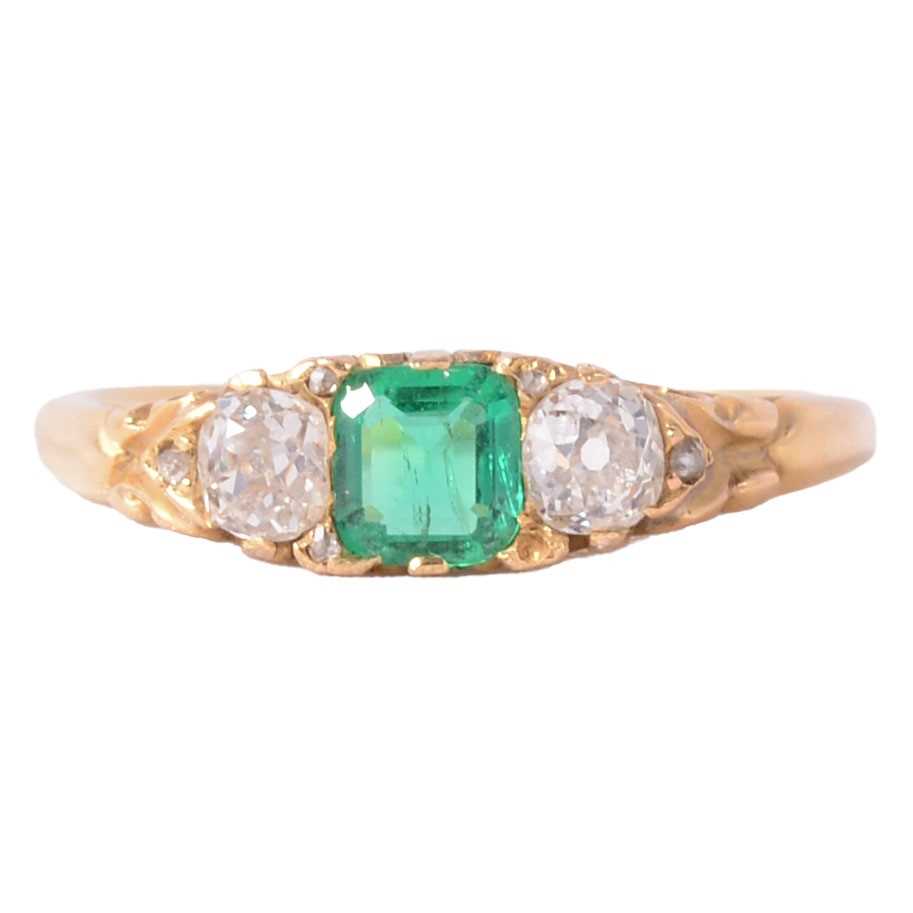 Lot 22 - An emerald and diamond three stone ring.