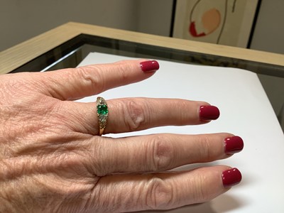 Lot 22 - An emerald and diamond three stone ring.