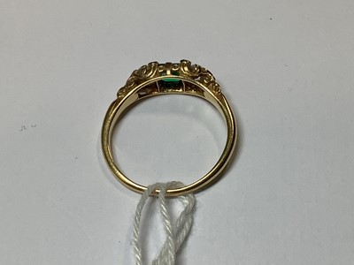 Lot 22 - An emerald and diamond three stone ring.