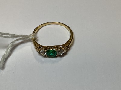 Lot 22 - An emerald and diamond three stone ring.