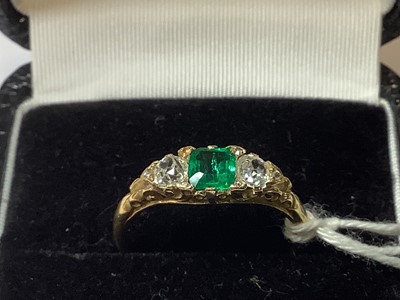 Lot 22 - An emerald and diamond three stone ring.