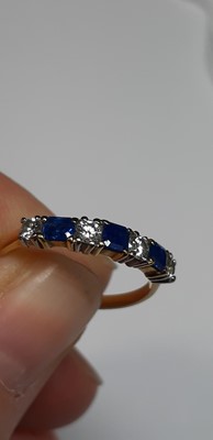 Lot 15 - A sapphire and diamond half eternity ring.