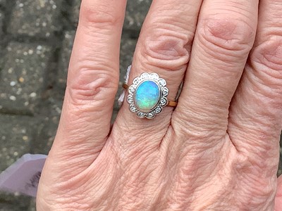 Lot 50 - An opal and diamond oval cluster ring.