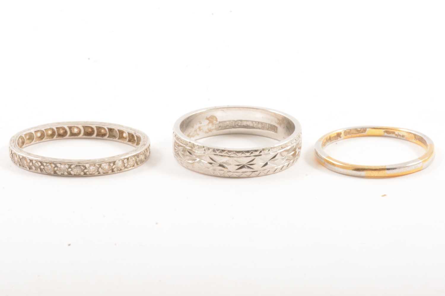 Lot 107 - A platinum wedding band, eternity ring and platinum and gold band.